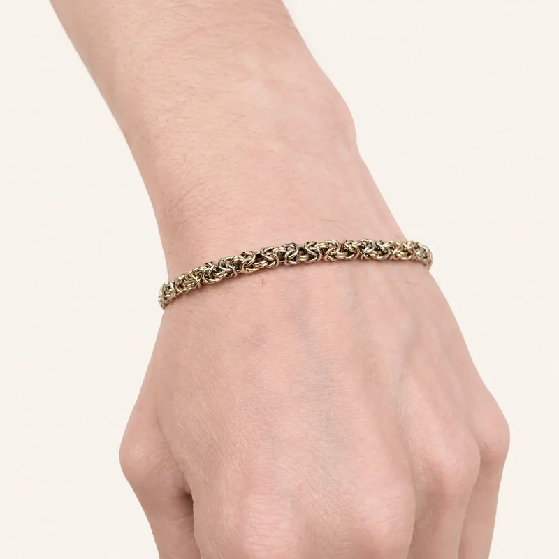 A tricolour royal chain bracelet on a wrist, hand-woven from 14k gold